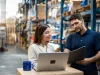Nulogy Warehouse manager and worker collaborating on laptop for efficient operations