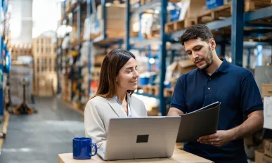 Nulogy Warehouse manager and worker collaborating on laptop for efficient operations