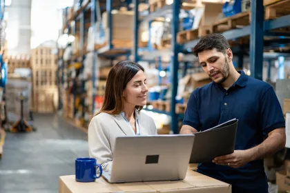 Nulogy Warehouse manager and worker collaborating on laptop for efficient operations