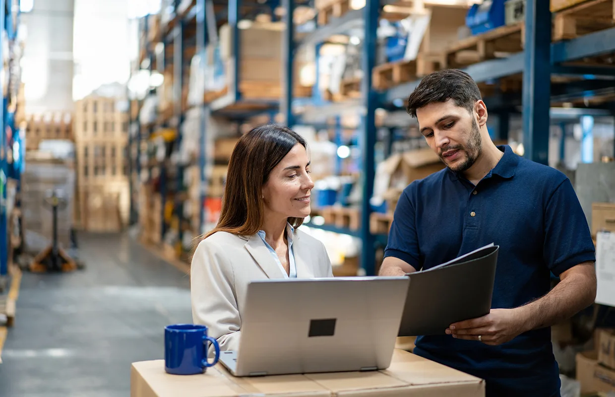 Nulogy Warehouse manager and worker collaborating on laptop for efficient operations