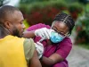 image of young african nurse in face mask, injecting young black