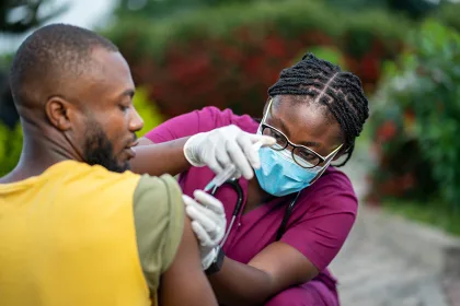 image of young african nurse in face mask, injecting young black