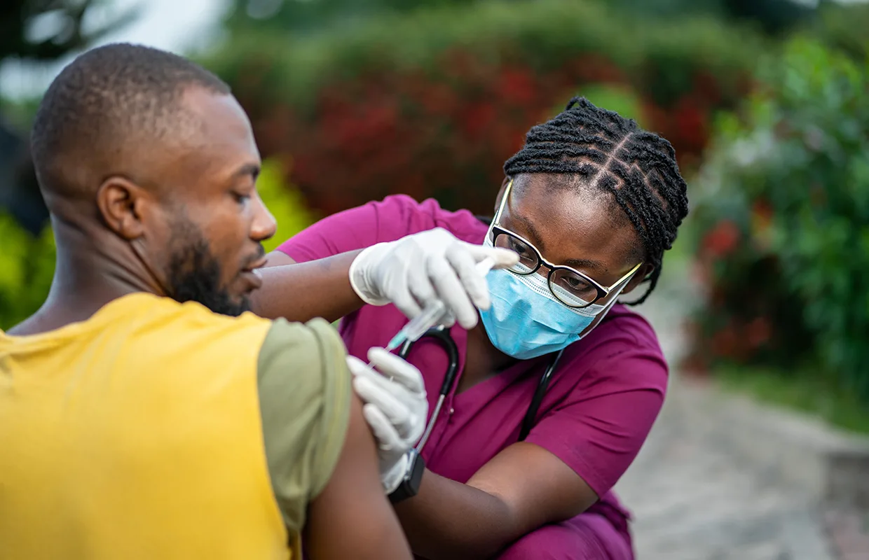 image of young african nurse in face mask, injecting young black